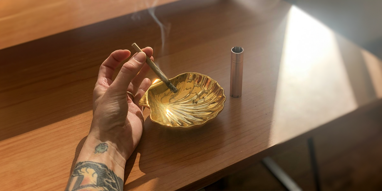 cannabis joint lit with gold shell ashtray