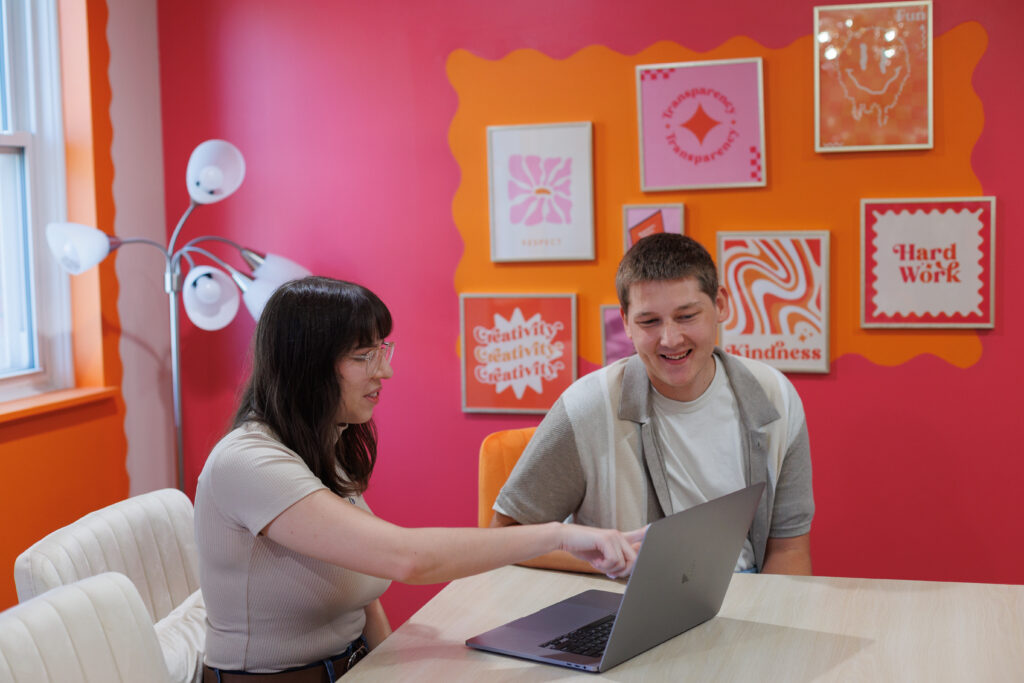 a woman and a man looking at a computer screen on a laptop